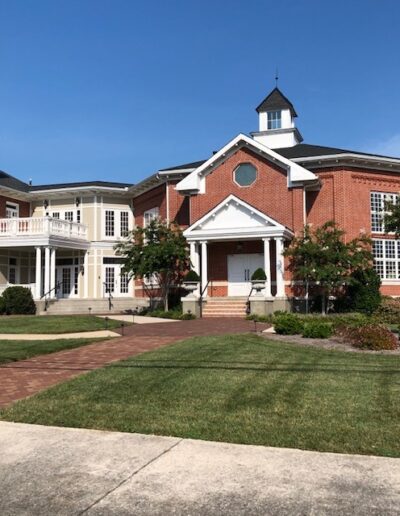 Traditional red brick building with white columns and a central cupola under a clear blue sky.