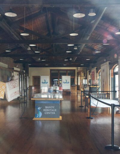 Interior of a heritage center with informational displays and wooden beams, viewed through a window.