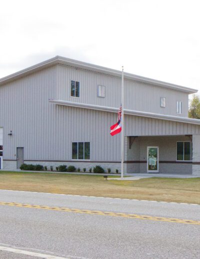 Modern fire station building with three garage bays and an american flag flying out front.